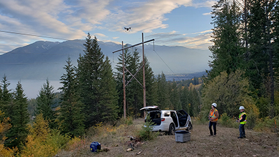 Two employees preforming an inspection of a transmission line using a drone